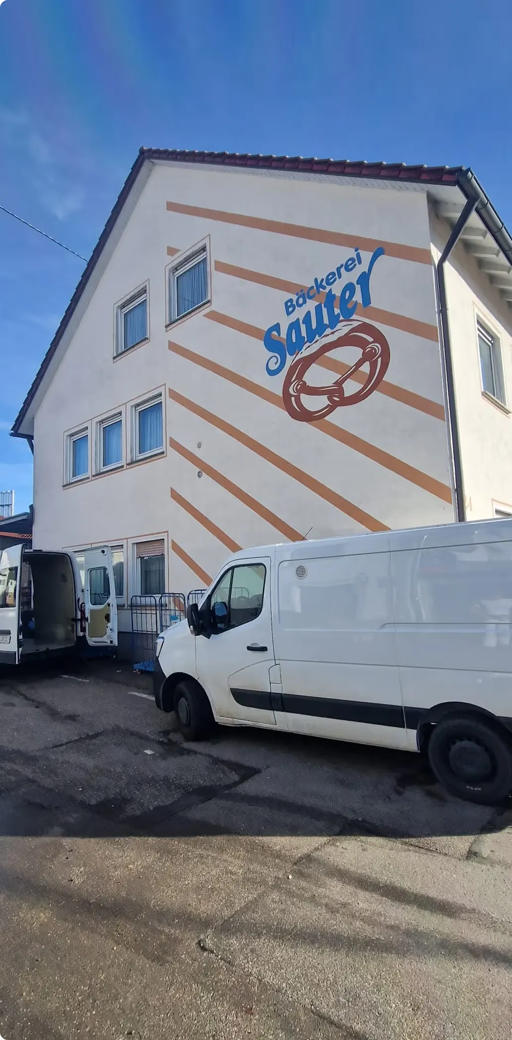 Fassade der Bäckerei Sauter mit Schriftzug, davor ein Lieferwagen