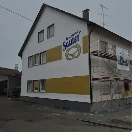 Bäckerei Sauter mit goldfarbenen Putzflächen, seitlich eingerüstet