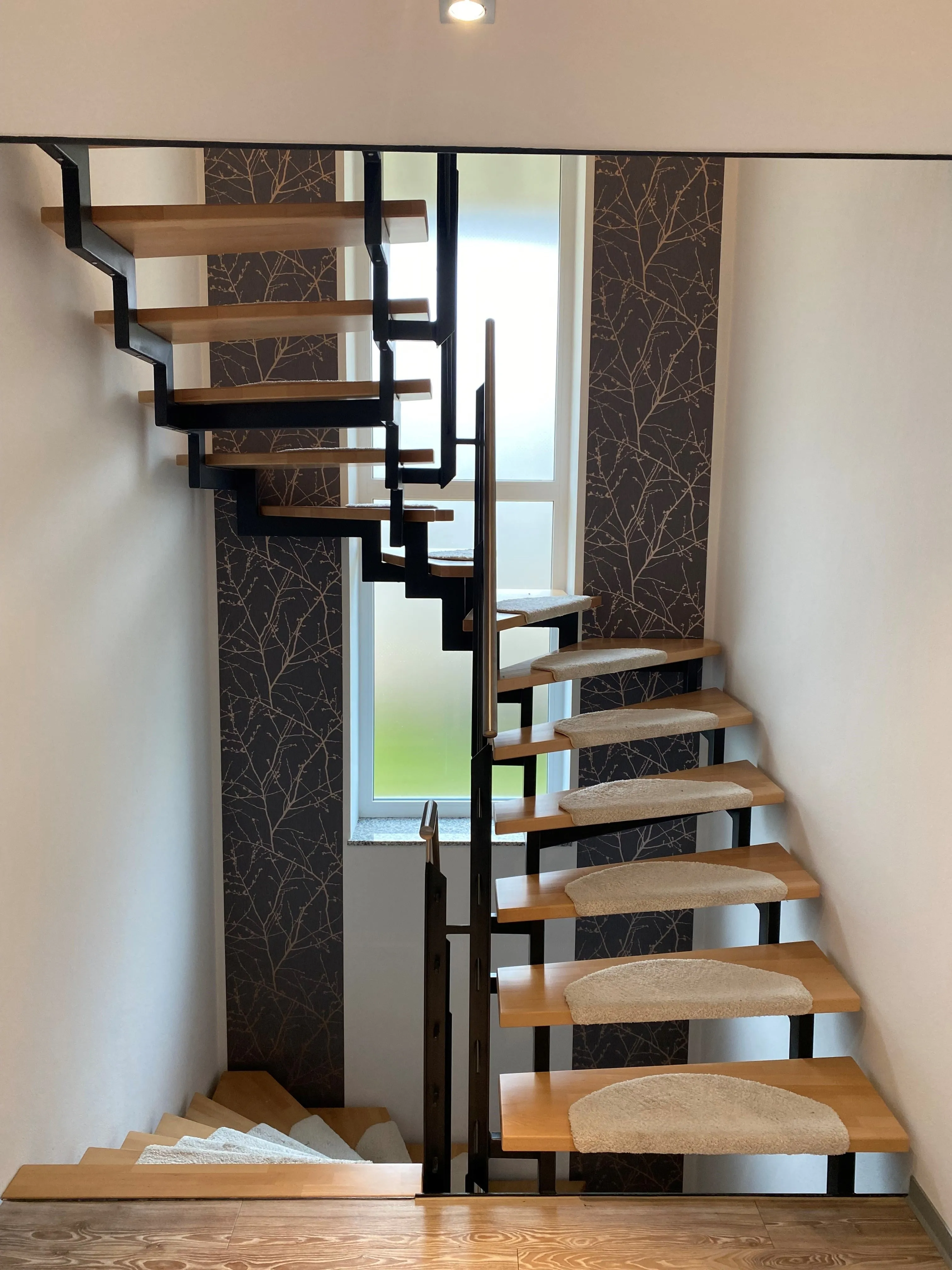Freitragende Holztreppe vor dunkel gestalteter Wand